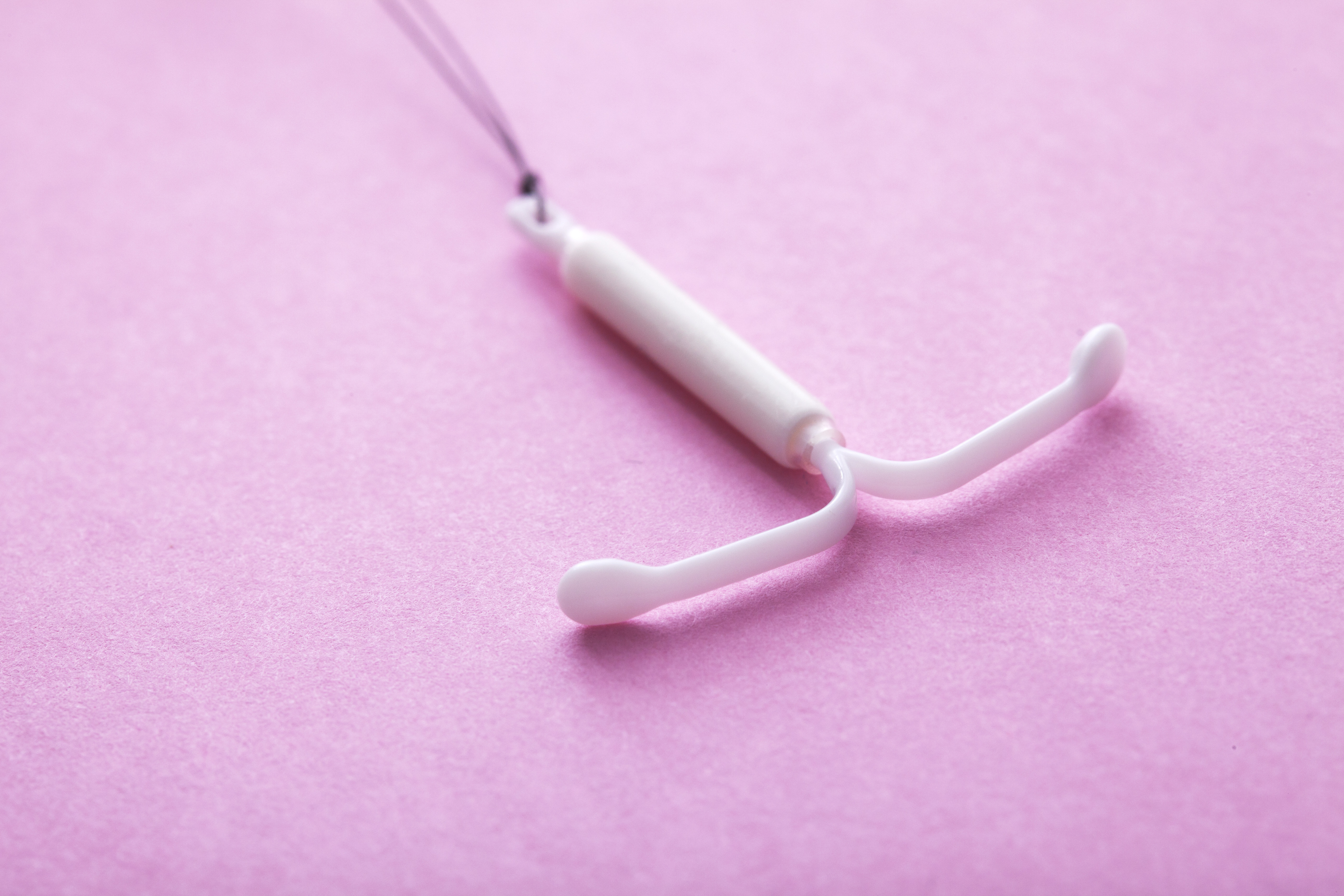 An IUD on a pink background.